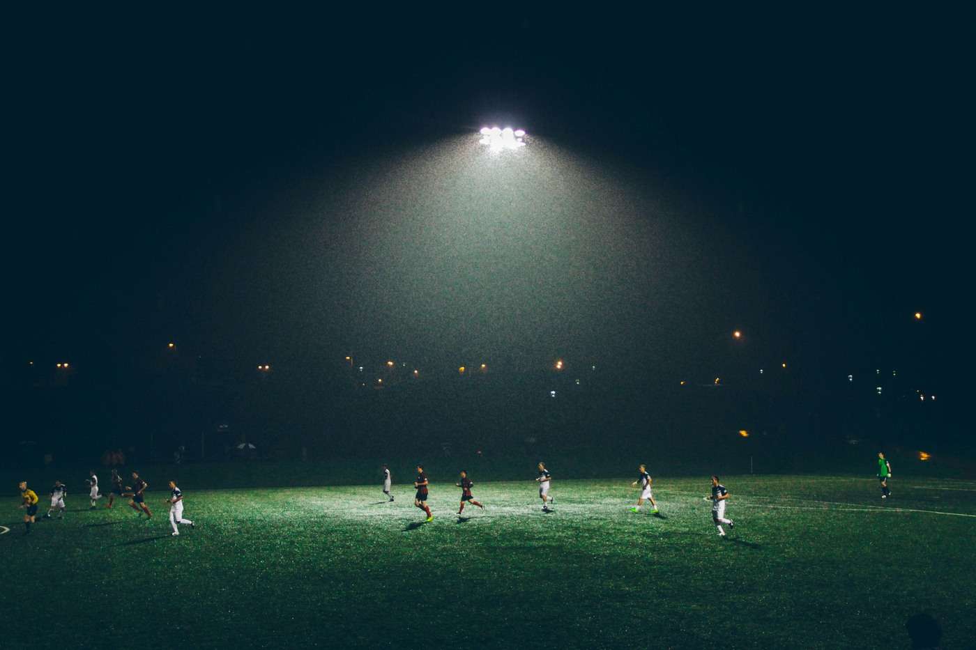 Soccer players running on a lit field during a match, representing soccer knee injury risk in Burlington athletes