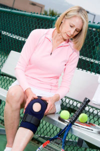 woman putting on knee band to play tennis