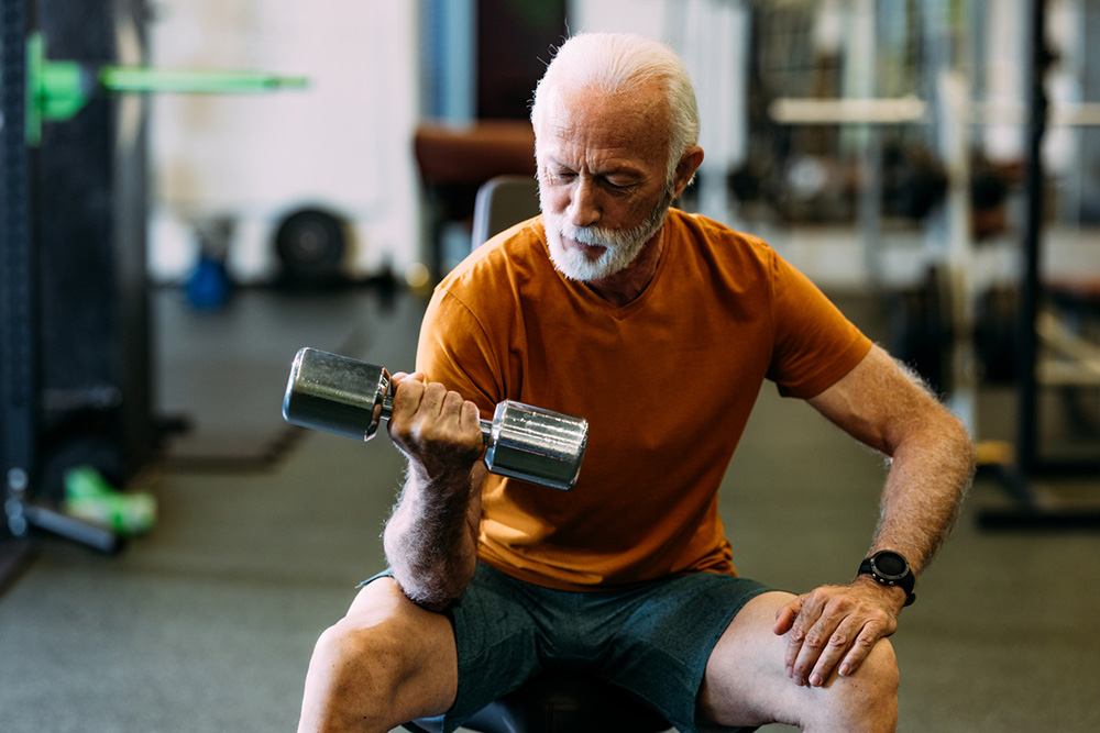 elderly man lifting dumbell at the gym